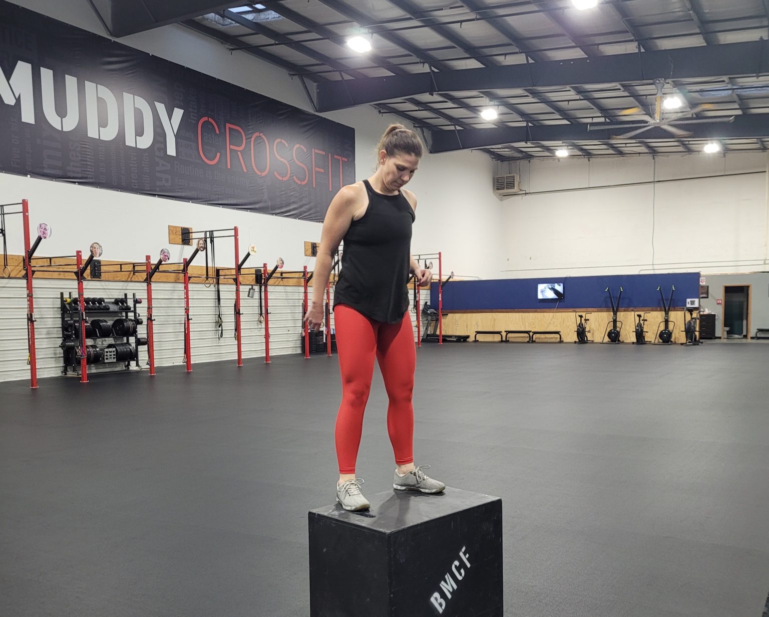 Woman stands on box in gym 